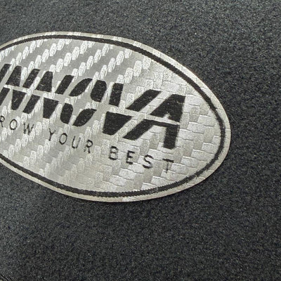 A silver Innova patch with black textured lettering that reads "INNOVA THROW YOUR BEST" is sewn onto black fleece material.