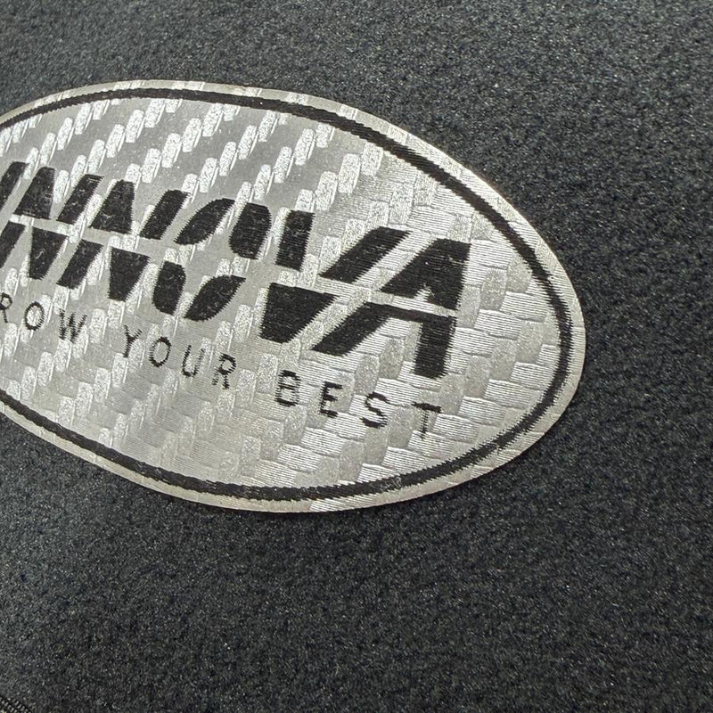 A silver Innova patch with black textured lettering that reads "INNOVA THROW YOUR BEST" is sewn onto black fleece material.