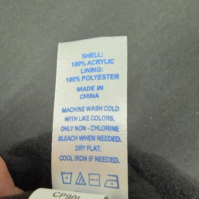 White laundry care tag for an Innova Flow Cuff Beanie with blue text and symbols listing acrylic and polyester.