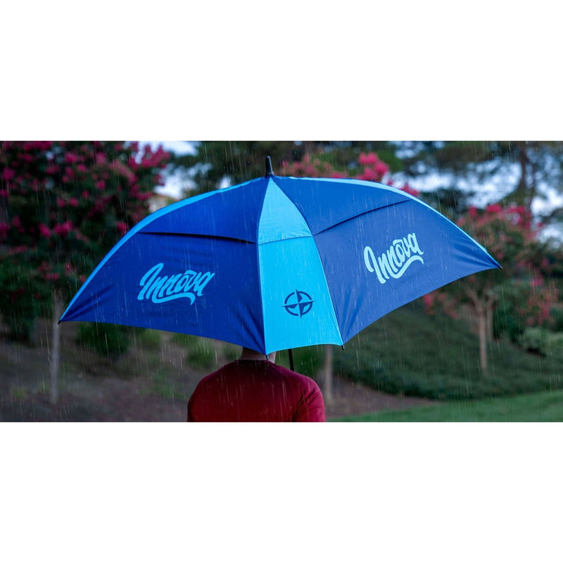 Two-toned Innova Flow Umbrella, featuring light blue and darker blue panels with Innova logos, protecting from rain.