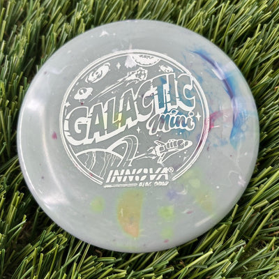 Light gray Innova "Galactic Mini" disc golf marker with multicolored burst swirls and a cosmic graphic print.