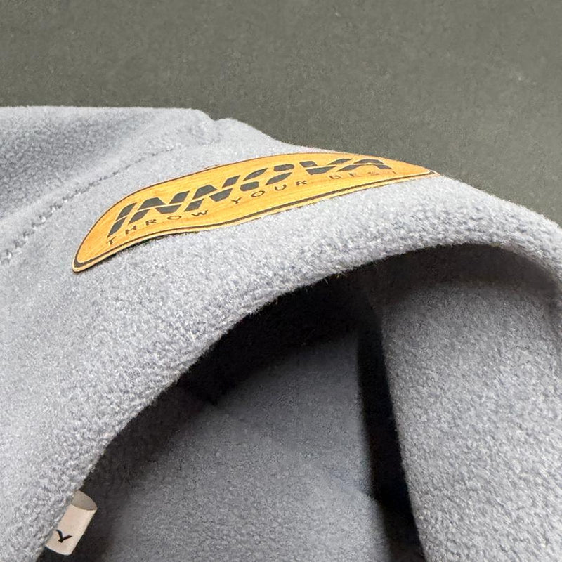 Gray fleece Innova beanie hat with a brown faux leather patch displaying the Innova logo and "THROW YOUR BEST".