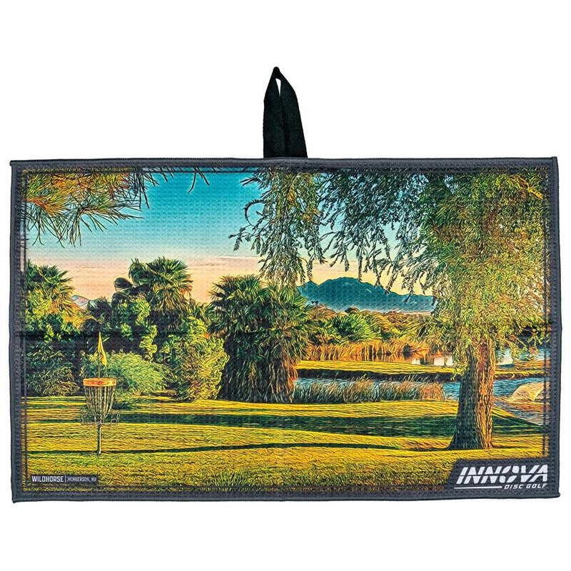 Gray Innova Wildhorse Tour Towel with a vibrant course landscape featuring trees and a disc golf basket.