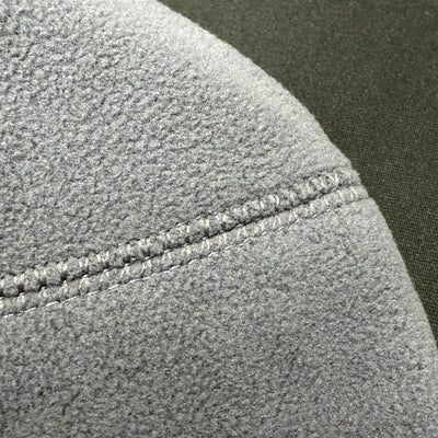 Close-up of a grey Innova fleece beanie with visible stitching on a seam, showing the texture of the material.