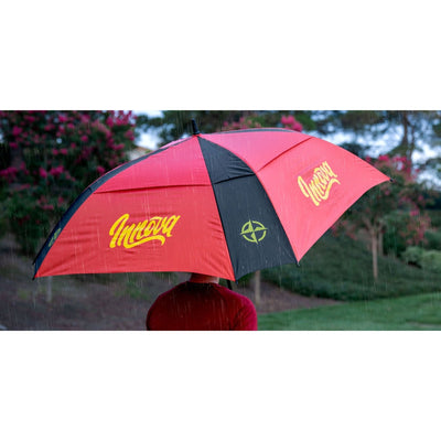 Red and black Innova Flow umbrella with a yellow Innova logo and a green compass rose design protecting a person from rain.