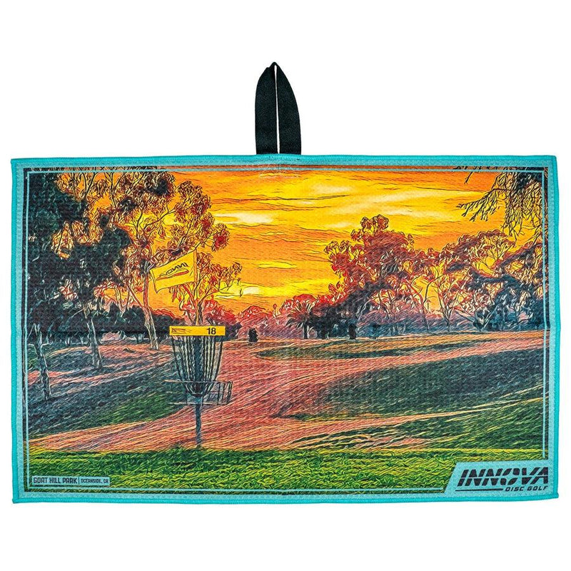 Innova Tour Towel featuring a vibrant sunset disc golf course with a basket and yellow flag, bordered in teal.