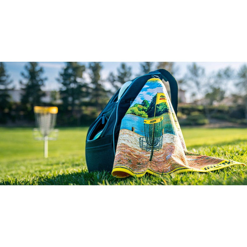 Dark green disc golf bag with a colorful Innova Winthrop Tour Towel featuring a disc golf basket and lake scene.