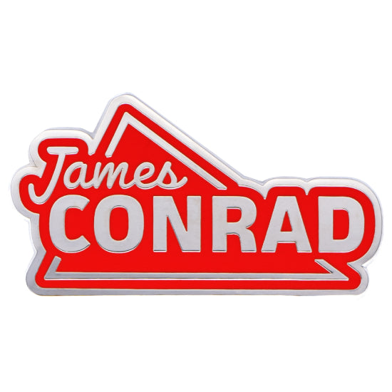 Red and silver James Conrad enamel pin with a distinct arrow design and embossed lettering.