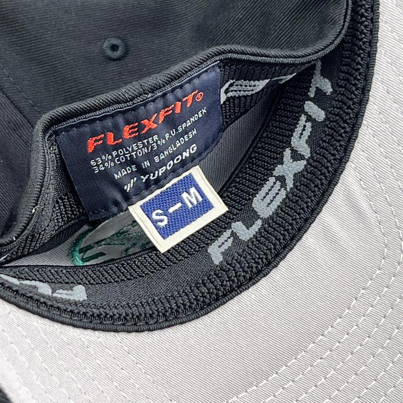 Black Flexfit baseball cap showing the interior labels and the light gray underside of the brim.