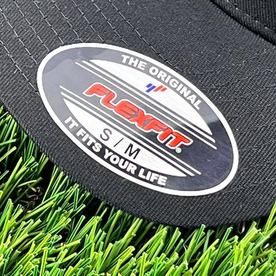 Black Flexfit hat with a white oval sticker, red and white Flexfit branding, and S, M sizing.