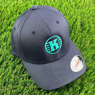 Black Flexfit Kastaplast cloth back hat featuring a vibrant teal "K" logo embroidered on the front.