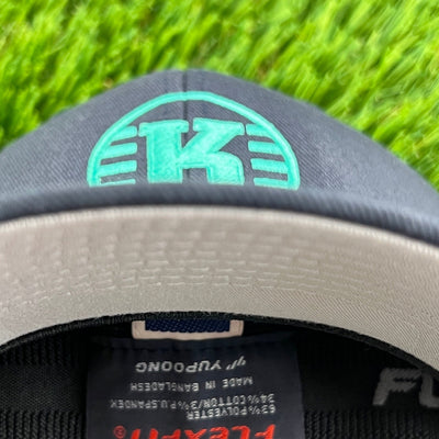 Dark gray Flexfit hat with a teal Kastaplast logo and a light gray underside to the brim.