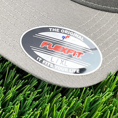 Neutral gray Flexfit sizing sticker on a light gray Kastaplast clothback hat with prominent stitching.