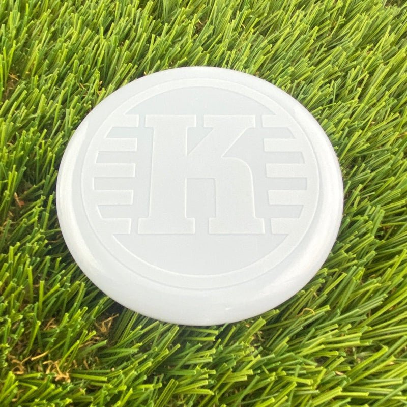 White Kastaplast K Mini Marker disc golf marker with a large embossed "K" logo centered on its surface.