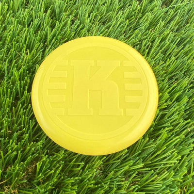 Bright yellow Kastaplast K Mini Marker disc golf disc with an embossed "K" logo on its smooth surface.