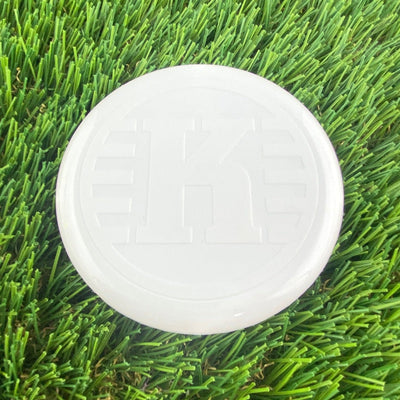 White Kastaplast K Mini Marker disc with an embossed K logo and a smooth, glossy surface.