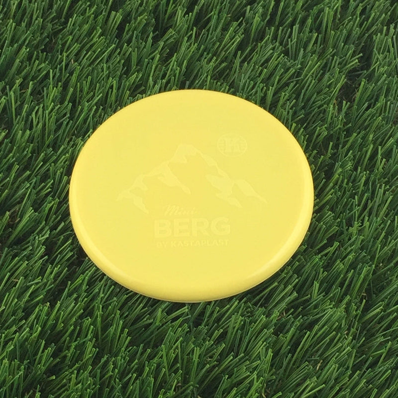Bright yellow Kastaplast Mini Berg marker disc featuring embossed mountain graphics and disc golf branding.