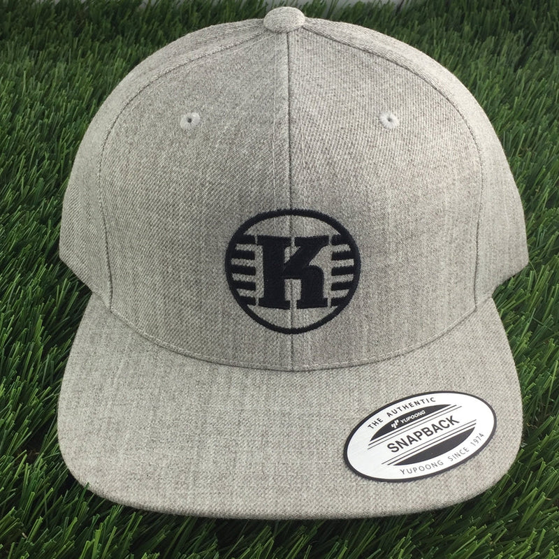 Light gray Kastaplast Snapback cloth hat with a black circular K logo and a Yupoong sticker on the brim.