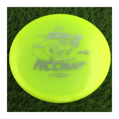 Translucent yellow Latitude 64 Opto X Glimmer Fuse disc with a metallic silver Johne McCray Team Series 2024 stamp.