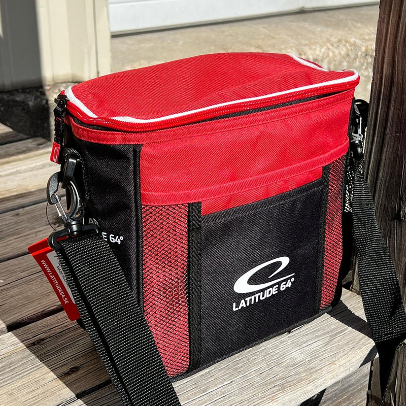 Red and black Latitude 64 Slim Bag with white zippers, two mesh side pockets, and an adjustable shoulder strap.
