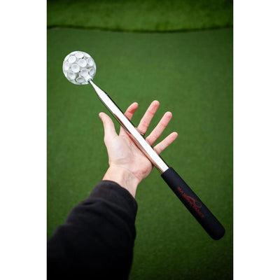 A person holds a silver Max Disctance metal Max Stick Gen 2 retriever with a white dimpled head and black handle.