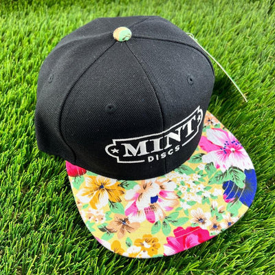 Black Mint Floral flat bill snapback hat with a white Mint Discs logo and a colorful floral print visor.