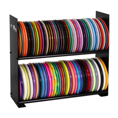 Black painted metal MVP Disc Station Lite with two shelves holding many colorful disc golf discs.