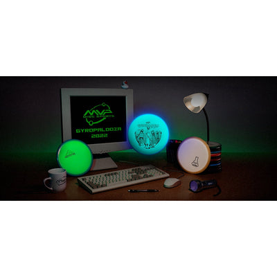 Three glowing MVP Gyropalooza 2022 mystery discs, two fluorescent and one off-white, are displayed on a dark desktop.