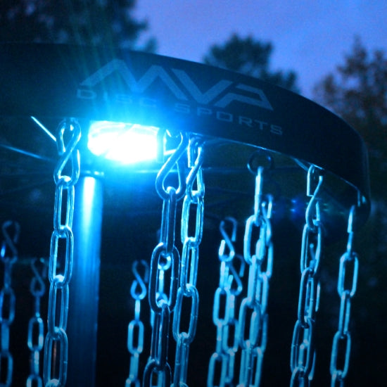 Mvp lunar module disc golf basket light with brightly glowing blue led, illuminating the silver chains and dark background.