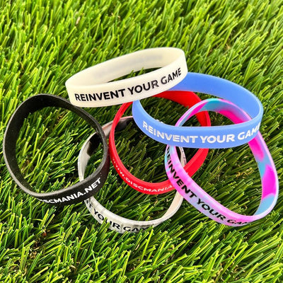 A pile of discmania "reinvent your game" silicone wristbands in white, black, red, light blue, and pink/teal tie-dye on.