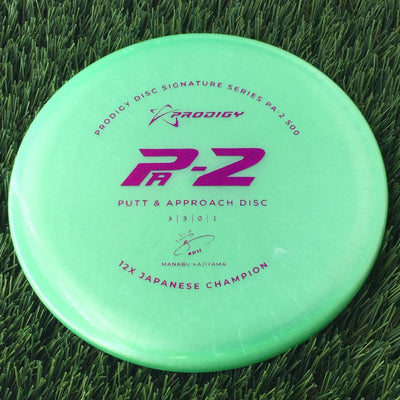 Solid green Prodigy PA-2 500 disc golf putter with 2022 Manabu Kajiyama 12X Japanese Champion signature stamp in magenta.