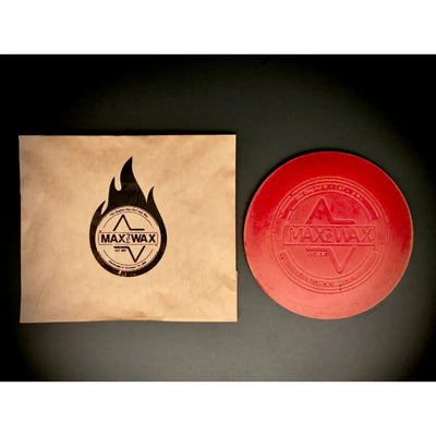 Red circular dg max wax mini grip wax with an embossed label next to its kraft paper packaging.