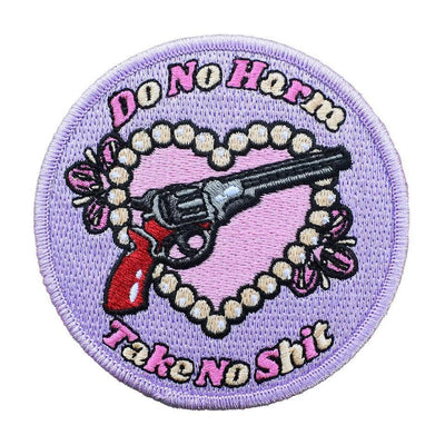 Purple woven patch with a pink heart, a black revolver, and "Do No Harm Take No Shit" embroidered text.