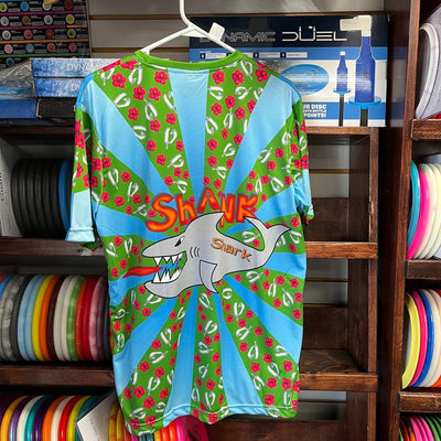 Vibrant green and blue jersey with radiating stripes, a large grey shark illustration, and "SHANK Shark" lettering.