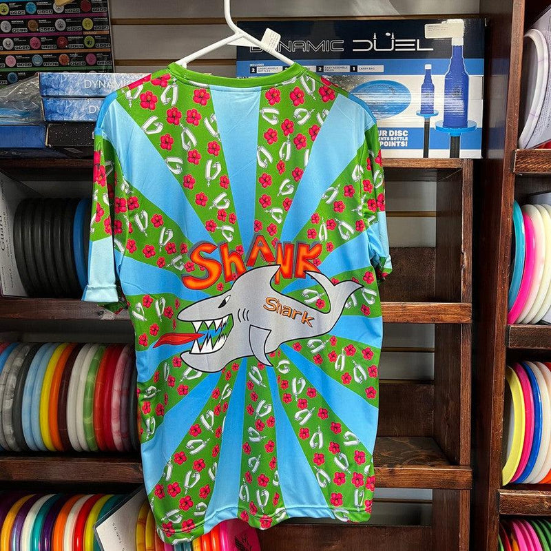 Vibrant green and blue jersey with radiating stripes, a large grey shark illustration, and "SHANK Shark" lettering.