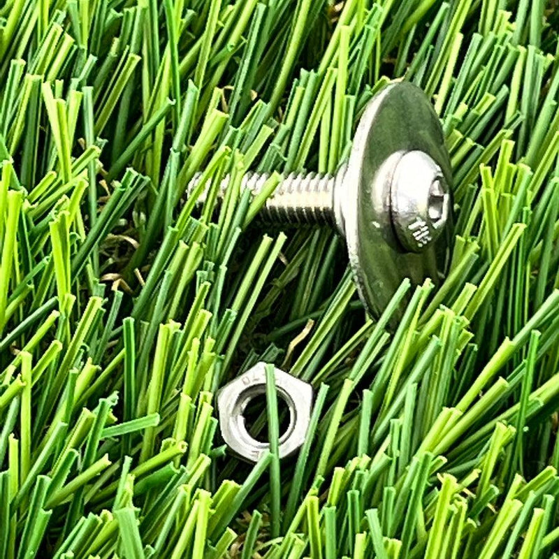 Shiny hans retriever tip with hexagonal bolt and loose nut, nestled in vibrant green artificial turf.