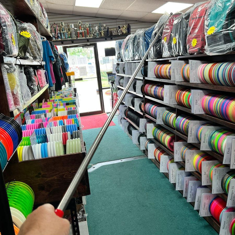 A shiny silver inzone kwik stik mini round hook with a red handle extends across a disc golf store.
