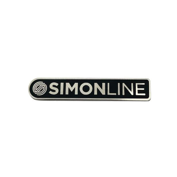 Black bar stamp enamel pin with a silvery white "SIMONLINE" logo and abstract swirl graphic.