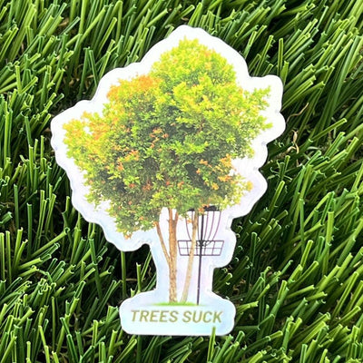 Holographic die-cut sticker depicts a tree with green and orange foliage beside a disc golf basket, with "TREES SUCK" text.
