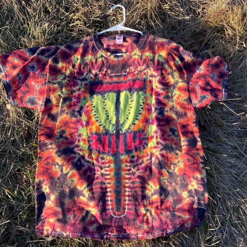 Tie-dye t-shirt featuring vibrant orange, red, and purple hues with a prominent green and red disc golf basket design.