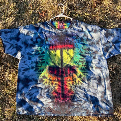 Tie-dye t-shirt with a vibrant, multicolored disc golf basket design on a blue and gray background.
