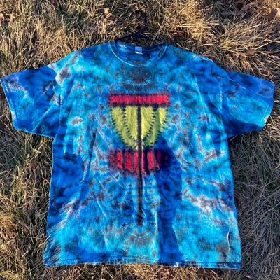 A vibrant blue tie-dye t-shirt features a large yellow and red graphic of a disc golf basket on the front.