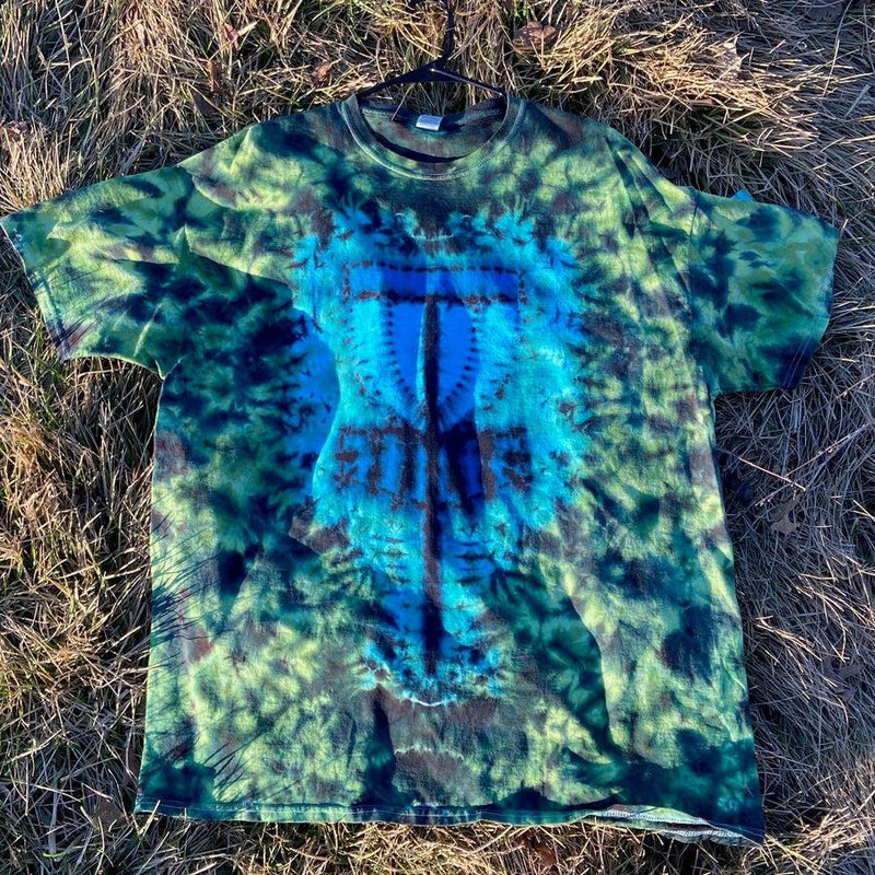 A tie-dyed t-shirt in shades of blue and green, featuring a centered blue disc golf basket design.