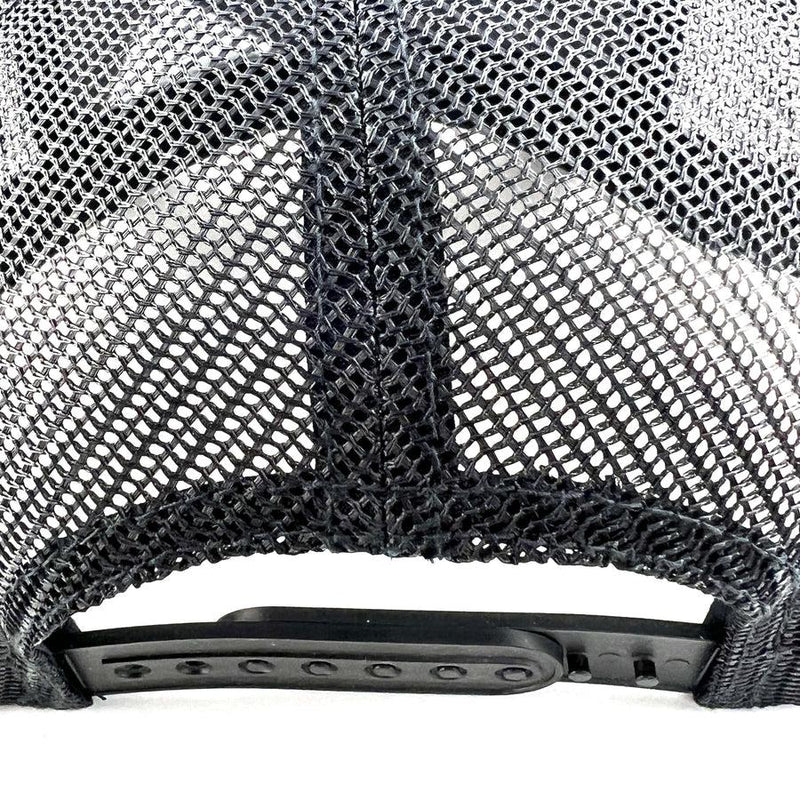 Close up of a black mesh Yupoong Axiom snapback trucker hat with a plastic adjustment strap.