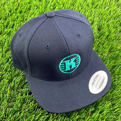 Dark navy Yupoong Kastaplast snapback clothback hat with a vibrant green "K" logo on the front.