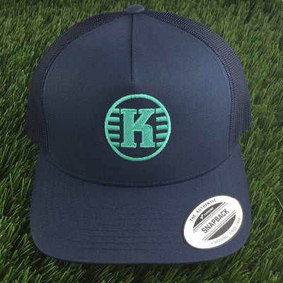 Navy blue Yupoong Kastaplast mesh back snapback hat with an embroidered green "K" logo on the front.