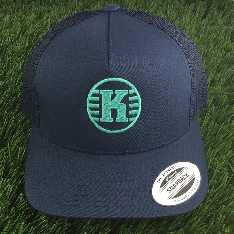 Navy blue Yupoong Kastaplast mesh back snapback hat with an embroidered green "K" logo on the front.