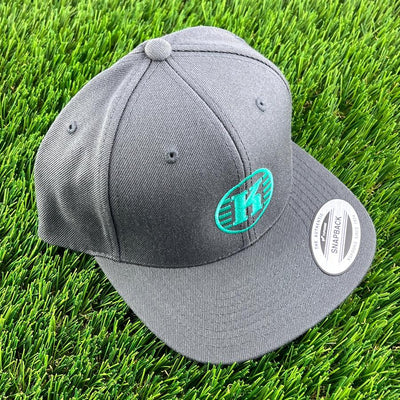 Gray Yupoong Kastaplast Snapback hat with a vibrant teal K logo and visible authenticity sticker.