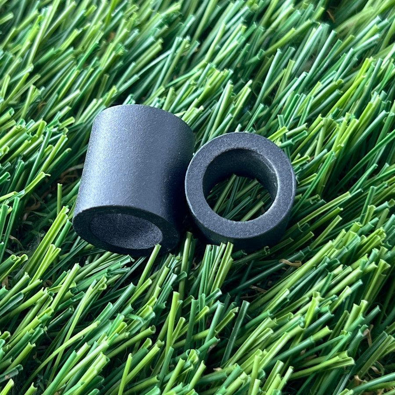 Two black Zuca backpack cart large wheel spacers, with cylindrical shapes and smooth matte surfaces.