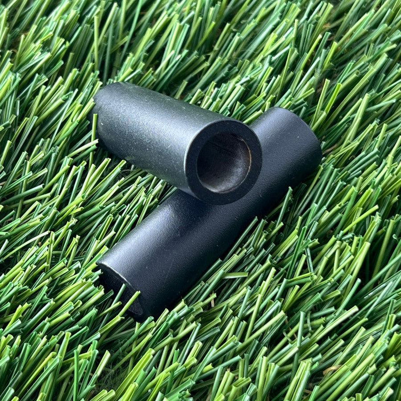 Two black Zuca cart wheel spacers, cylindrical with hollow centers, are angled on a textured surface.